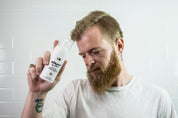 beard wash travel size with a man holding it