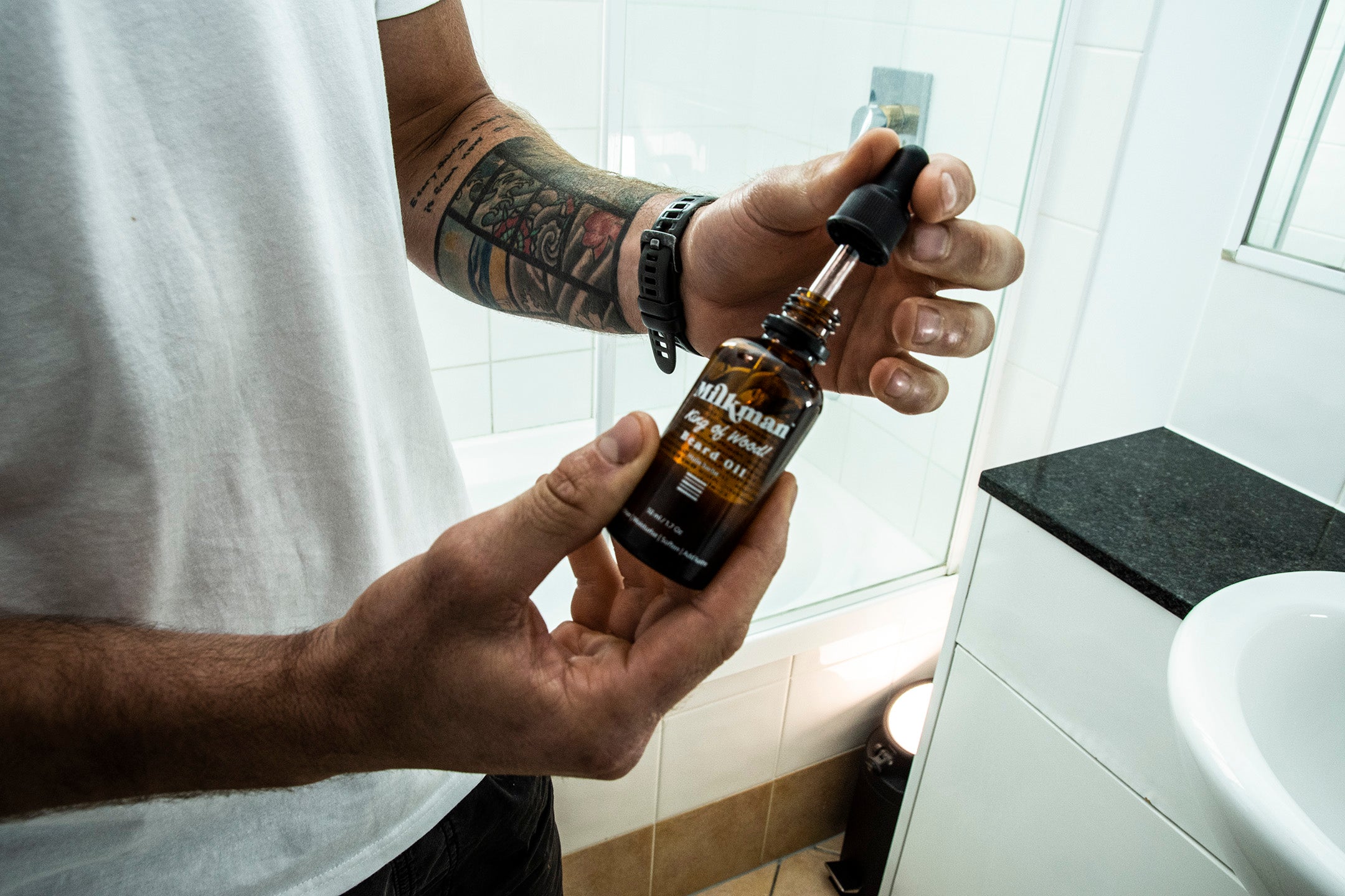 man holding Milkman King of Wood beard oil in the bathroom