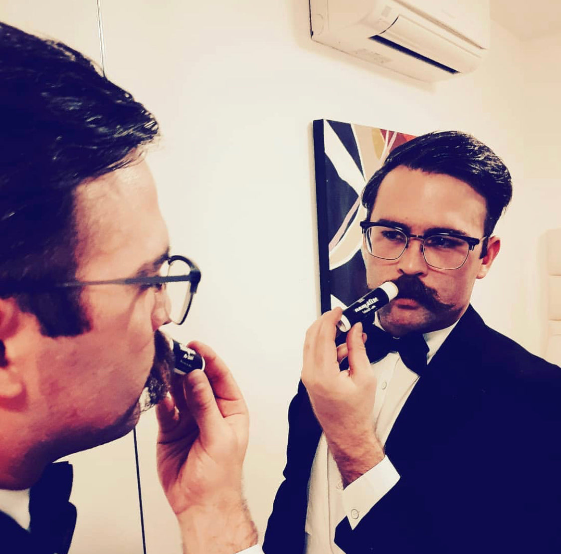 man using milkman moustache wax in the mirror